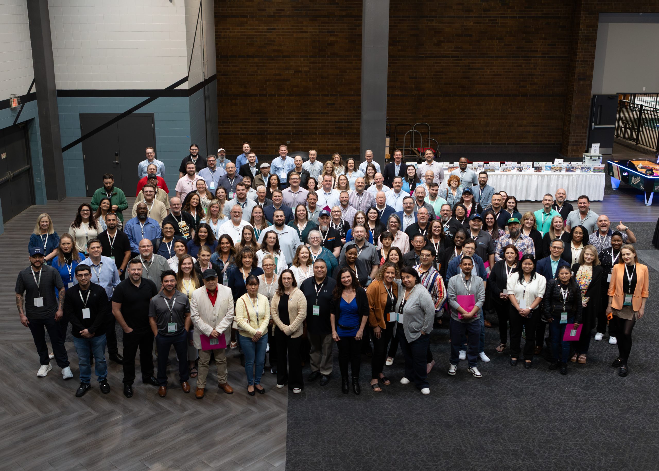 Large group of professionals posing for a group photo in a conference hall, many wearing badges on lanyards.